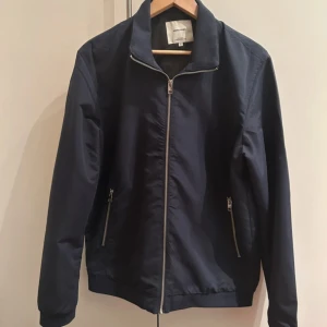 Mörkblå vindjacka från Jack & Jones - Väldigt fin jacka, passar bra t höst/vår, storlek L men passar även M. Mycket mycket bra skick 