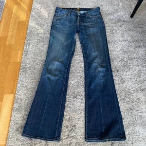 Bootcut jeans - Jätte Snygga bootcut lågmidjade jeans från 7 For All Mankind med coola guld detaljer på bakfickorna, säljer då de inte passar mig längre. Midjemåttet 38cm rakt över och innerbensmåttet 82cm