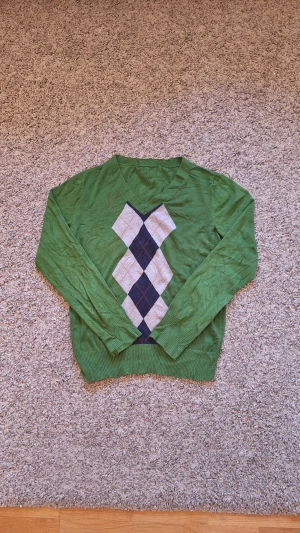 Grön stickad tröja - Grön stickad tröja i storlek S med mönster. Använd många gånger och skicket är bra. Den har dock ett hål på nacken (bild 4,5) som knappts syns och det påverkar inte skicket. Riktig skön nu inför vintern då den är varm och stilig. 