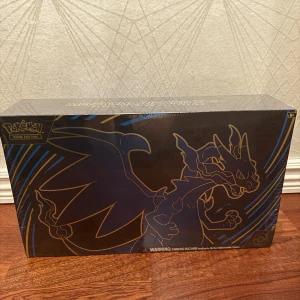 Pokémon TCG Mega Charizard X ex Ultra-Premium Collection - Mega Charizard X ex Ultra-Premium Collection för Pokémon TCG, fabriksförseglad och i nyskick. Innehåller exklusiva promokort, booster packs, sleeves, lekmatta och samlarbox med Charizard-design. Perfekt för samlare och spelare, åldersrekommendation 6+.