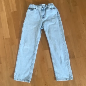 Ljusblå jeans från Grunt - Säljer ett par ljusblå jeans från Grunt, modellen Haman Acid Jeans. De har en rak passform med klassiska fem fickor och hög midja. Jeansen är tillverkade i ekologisk bomull och har en snygg acid wash som ger en cool vintage vibe. Köpta på kidsbrandstore för 800kr.