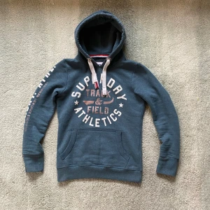 Superdry hoodie  - En riktigt fet hoodie ifrån Superdry med ett riktigt schysst tryck. Tröjan är använd men har ej några defekter. Storlek S. Har du några frågor kring mått osv? Fråga på 
