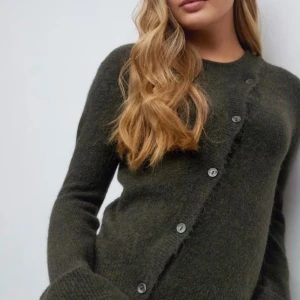 SÖKER Mörkgrön kofta i ull med knappar - SÖKER Snygg mörkgrön kofta i mjuk ull med rund halsringning och knappar framtill. Långärmad modell med en lite fluffig känsla och klassisk passform. Perfekt att slänga över en t-shirt eller bära som den är.SÖKER FÖR RIMLIGT PRIS
