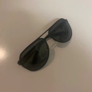 Solglasögon Svarta - Snygga svarta pilot-solglasögon med polariserade linser och UV400-skydd. Metallbågar med klassisk aviator-form och mörka glas. Perfekt för soliga dagar och ger en cool vibe till din stil. PRISET KAN DISKUTERAS.