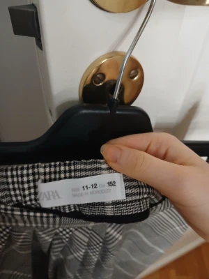 Rutig kortkjol från Zara, svartvit - Snygg kortkjol från Zara i svartvitt rutigt mönster. Kjolen har en elastisk midja och är lätt utställd för en cool och ungdomlig look. Perfekt att matcha med en enkel topp eller hoodie. Materialet känns mjukt och bekvämt mot huden.