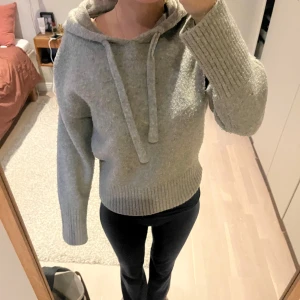 Grå stickad hoodie från Zara - Mysig grå hoodie från Zara i stickat material med huva och snörning. Tröjan har ribbade muddar vid ärmslut och nederkant. Använt få gånger och är i bra skick. 