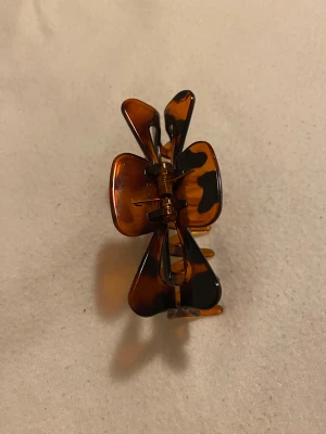 Hårklämma - brun genomskinlig med svarta fläckar - Säljer en snygg hårklämma i brun genomskinlig plast med svarta fläckar. Knappt använd och i superfint skick!  Perfekt för att hålla håret på plats med stil, passar både vardag och fest. Frakt kan tillkomma.