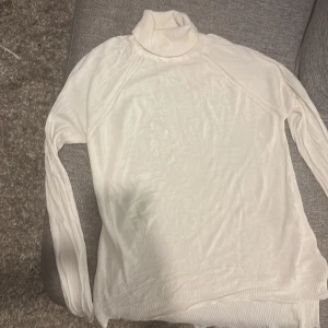 Vit polotröja från Alvina - Säljer en vit polotröja från Alvina i storlek 40. Tröjan har lång ärm och en ribbad, hög krage som ger en clean och stilren look. Materialet är stickat och känns mjukt mot huden. Perfekt för dig som gillar klassiska och enkla plagg. Längre baktill än framtill snygg. 