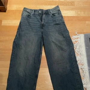 Baggy svarta jeans från H&M - Säljer ett par svarta baggy jeans från H&M i storlek 28/32. Jeansen har klassisk femficksdesign, raka ben och en avslappnad passform. Perfekta för dig som gillar en loose och trendig stil. Materialet är klassisk denim i bomull.