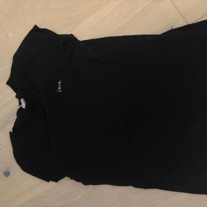 Svart t-shirt med broderad text - Svart t-shirt i mjuk bomull med korta ärmar och liten broderad text 'love' på bröstet. Enkel och stilren design som passar perfekt till jeans eller shorts. T-shirten har rund hals och är skön att bära hela dagen.