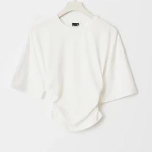 Vit t-shirt med scrunch från Gina Tricot - Vit t-shirt som går in i midjan från Gina Tricot i storlek XS. Modellen har korta ärmar, rund halsringning och snygg scrunch i sidorna som ger en cool twist. Tillverkad i mjuk bomull för en skön känsla. Perfekt till jeans eller kjol. Superbra skick, inga tecken på användning 