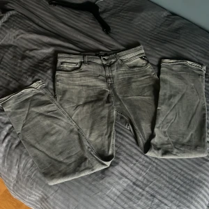 Replay grå jeans straight fit - Snygga grå jeans från Replay med klassisk femficksdesign och raka ben. Jeansen har en cool tvättad look, svarta detaljer och logopatch bak i midjan. Passar dig som gillar stilrena och tidlösa jeans med lite edge.