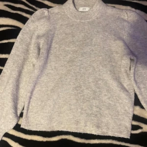 Ljusgrå stickad tröja från JDY - Mysig ljusgrå stickad tröja från JDY i storlek XS. Tröjan har puffade axlar, ribbad hals och muddar vid ärmslut och nederkant. Perfekt för dig som gillar enkel och stilren look med en liten twist på axlarna.PRIS KAN DISKUTERAS💗💗