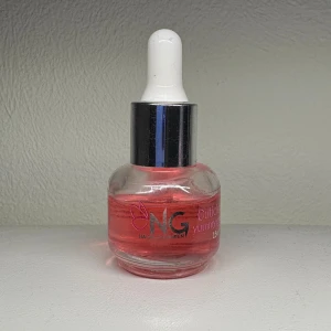 NG Cuticle Oil Yummy Strawberry - Säljer en söt rosa nagelbandsolja från NG Nagelgiganten med doft av jordgubb. Kommer i en rund glasflaska med pipett för enkel applicering. Perfekt för att vårda och återfukta nagelbanden.