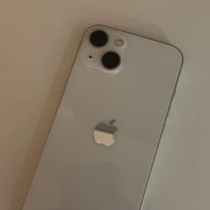 iPhone 13 - Snygg vit iPhone 13 med dubbla kameror och stilren design. Mobilen ser ut att vara i gott skick utan synliga repor eller skador på baksidan. Perfekt för dig som vill ha en kraftfull och modern smartphone med hög bildkvalitet och pålitlig prestanda. Inga sprickor eller repor😊❤️