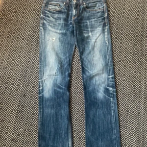 Straight Cocker Jeans with fading - 100 % bomull, låg midja, raka Crocker-jeans! Cirka 20 år gamla med riktigt snygg denimslitage och tydliga “whiskers” (veckmönster). Eftersom detta är en second hand-vara kan det finnas små brister, men jag har inte märkt några och därför inte nämnt några. Skicka gärna ett meddelande om du har frågor eller vill föreslå ett pris.  Mått (+/- 1cm) Midja: 41cm (W30) Innerbenslängd: 85cm (L34)  Total Längd: 108cm Rise: 23cm Låt: 25cm Ben öppning: 19cm Material: 100% cotton  Bilder av: manne_af