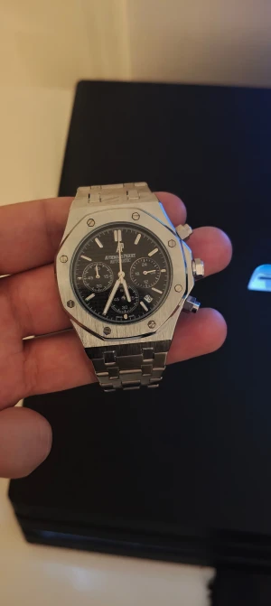  herrklocka - Säljer en Audemars Piguet Royal Oak herrklocka med oktagonal boett i borstat stål och svart urtavla med kronograf. Länken är i matchande stål och klockan har tydliga index och datumvisning. Perfekt för dig som gillar exklusiv design och detaljer.