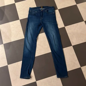 Blå skinny jeans från Lee - Snygga blå jeans från Lee med klassisk femficksdesign och gul kontrastsöm. Modellen är skinny med smal passform och normal midja. Jeansen har Lee-logga på bakfickan och är tillverkade i mjukt jeanstyg som sitter skönt hela dagen.W30 L32
