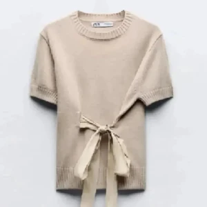 Beige stickad topp med knyt från Zara - Superfin beige stickad topp från Zara med korta ärmar och snyggt knytband i midjan. Använd fåtal gånger