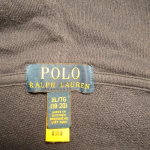 Blå hoodiejacka från Polo Ralph Lauren - Säljer en marinblå zip hoodie från Polo Ralph Lauren med vit broderad logga på bröstet. Tillverkad i bomull