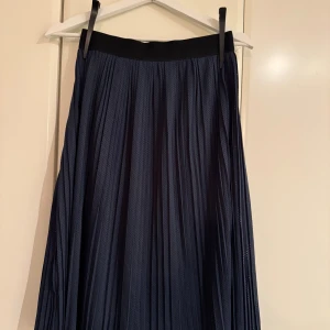 Mörkblå plisserad långkjol - Snygg mörkblå plisserad långkjol i ”sportigare” material. 