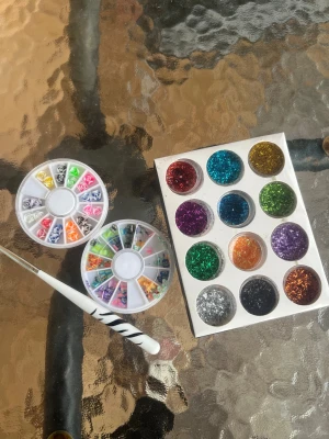 Färgglatt glitter och nagelborste  - Säljer ett set med tolv burkar glitter i olika färger som rött, blått, guld, grönt, lila, silver och svart, perfekt för kreativa naglar . Medföljer även en vit borste med svart mönster. 
