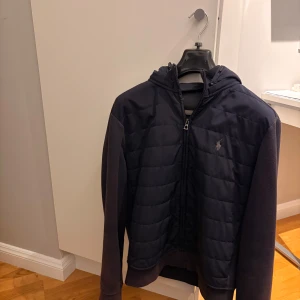 Ralph Lauren Cardigan - Marinblå cardigan från Ralph Lauren i riktigt bra skick. Bra kvalitet, enkel att styla och med den klassiska loggan framtill. Perfekt att slänga på både till vardag och när man vill vara lite extra fin.