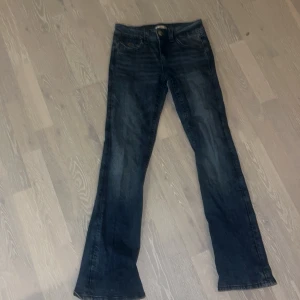 Y2k blåa jeans - Snygga blå jeans med bootcut passform  med paljetter på bakfickorna. Jeansen har klassisk femficksdesign, knapp och dragkedja fram för en trendig look. Perfekta för dig som gillar lite extra detaljer.