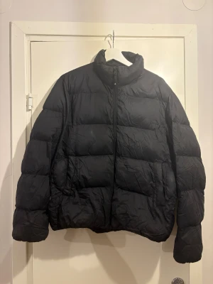 Svart pufferjacka från Cross Sportswear - Svart pufferjacka från Cross Sportswear med hög krage och dragkedja framtill. Jackan har ett stilrent, quiltat mönster och är tillverkad i syntetmaterial. Perfekt för kalla dagar med sin tjocka och fluffiga design.