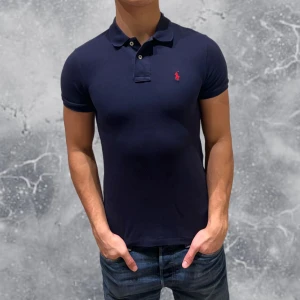 Ralph Lauren Piké Navy Blå - •Ralph Lauren Piké Navy Blå. Skick: 8-9/10, Inga skador. Storlek: 14/16 år, slim-fit (160-70 cm~). Modell: 174 cm, 63 kg. Authentic: ✅, QR-Kod finns även i plagget. Hör av dig vid frågor eller funderingar, mvh Hessler’s;)