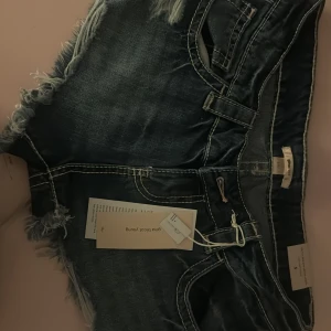 Lågmidjade jeanshorts - Säljer ett par mörkblå, lågmidjade jeansshorts från Gina Tricot. De är helt nya inte ens rörda sen sommaren bara provade, stor i storleken. 