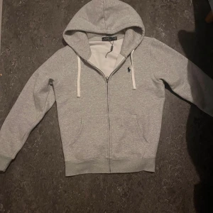 Ralph lauren kofta - Väldigt fin ralph lauren kofta i helt nytt skick, en fin grå färg som passar det mästa. Strlk S         Hojta till vid minsta fråga är även öppen för byten!!!