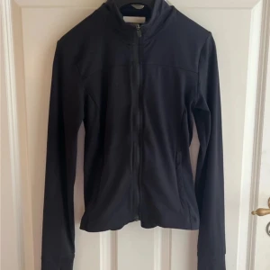 Svart ziptröja - Svart långärmad ziptröja i storlek XS med hög krage och tumhål vid ärmsluten. 