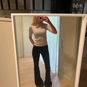 Beige ribbad topp - Säljer en beige ribbad topp med rund hals och korta ärmar. Toppen har en slim passform och är tillverkad i ett mjukt, stretchigt material som sitter snyggt på kroppen. Osäker på om jag vill sälja