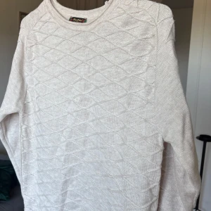 Beige stickad tröja från MaxPolo - Säljer en beige stickad tröja från MaxPolo i storlek L. Tröjan har ett snyggt strukturmönster med långa ärmar och rund hals. Material bomull.  Myckrt bra skick, inga noppror eller defekter. 