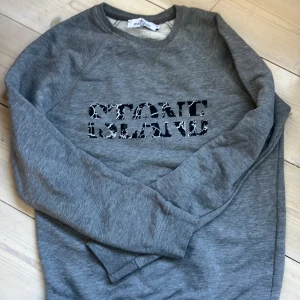 Grå sweatshirt från Stone Island - Säljer en grå sweatshirt från Stone Island med svartvit logga framtill. Tröjan har rund halsringning och långa ärmar. 