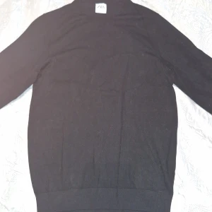 Svart polotröja från Zara - En svart polotröja från Zara i klassisk modell. Tröjan har lång ärm och hög krage, perfekt för lager-på-lager. Enkel och stilren design som funkar till det mesta. Materialet känns mjukt och smidigt.