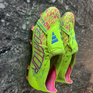 Adidas Predator fotbollsskor new edition  - Säljer ett par Adidas Predator fotbollsskor i neon-gul med blå detaljer och rosa mönster. Skorna har låg profil, snörning och är tillverkade i syntetmaterial. Nysatte modellen skriv om fler frågor eller funderingar. Vid snabb affär kan priset diskuteras. 