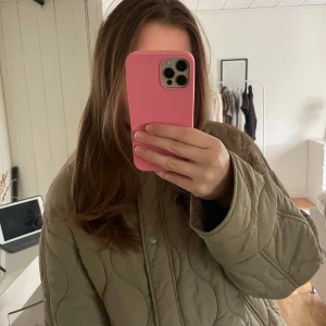 Quiltad jacka från H&M XS - Quiltad khaki jacka från H&M i storlek XS. Jackan har rund halsringning, tryckknappar framtill och en loose passform. Tillverkad i polyester och perfekt för lager-på-lager. Snygg vågig quiltning och långa ärmar ger en trendig look.