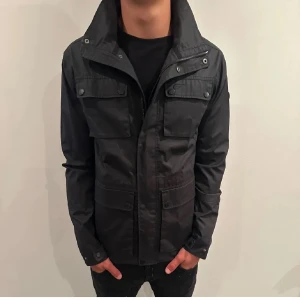 Field Jacket - Field jacka från Five Seasons, perfekt till hösten. Jackan har knappar och dragkedja, samt justerbar nederkant. Fint skick utan defekter, Pris kan möjligtvis diskuteras.