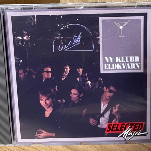 Eldkvarn - Ny Klubb CD - Upptäck Eldkvarns album 'Ny Klubb' – en samling låtar med klubbkänsla och nattlivsvibbar. Perfekt för dig som gillar musik med känsla och vill ha något unikt i samlingen. Innehåller låtar som 'Ung Kärlek', 'Hej, Älskling' och 'Dans, Dans, Dans'.