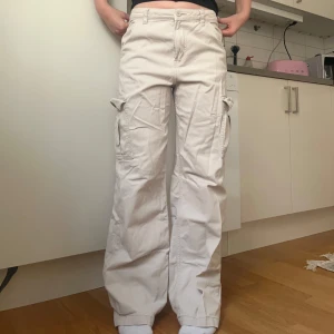Beiga cargopants från HM, stl 36 - Säljer ett par beiga cargopants från HM i storlek 36. Byxorna är vida, har stora fickor på sidorna och klassisk cargostil. Tillverkade i bomull.