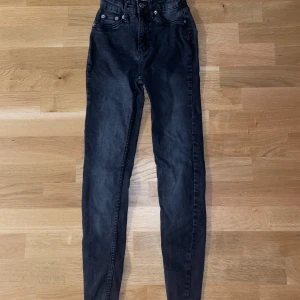 Svarta skinny jeans från 157 - Svarta skinny jeans från 157 med klassisk femficksdesign och hög midja. Jeansen har smal passform, bälteshällor och dragkedja med knapp framtill. Materialet är stretchigt jeans för en bekväm känsla och snygg siluett.