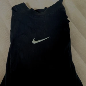 Svart Nike t-shirt loose fit XL - Svart t-shirt från Nike i loose fit-modell med klassisk vit swoosh-logga på bröstet. Tillverkad i mjuk bomull och passar dig som gillar en avslappnad och stilren look. Perfekt till jeans eller shorts.