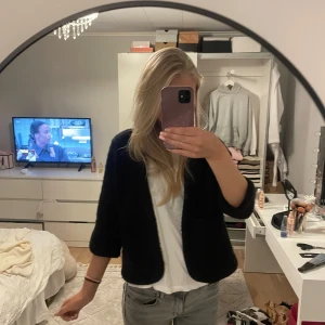 Svart stickad kofta från H&M - Mysig svart stickad kofta från H&M i storlek 34. Koftan har trekvartsärmar och en enkel, öppen design utan knappar. Perfekt att slänga över en t-shirt för en chill och stilren look.