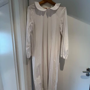 Ett vitt lucialinne från Mywear - Långt vitt lucialinne från Mywear Young i bomull med klassisk rund krage och långa ärmar med resår vid handlederna. 