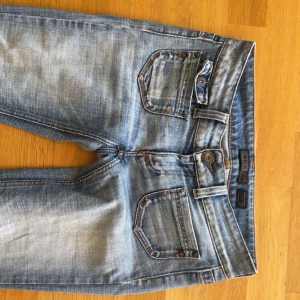 Bootcut jeans från ONLY W28 L34 - Snygga ljusblå bootcut jeans från ONLY med slitningar och klassiska fem fickor. Jeansen har låg midja och är tillverkade i mjukt denimtyg med lite stretch. Perfekta för dig som gillar en avslappnad men trendig look.