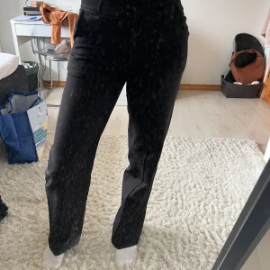 Svarta kostymbyxor med raka ben - Säljer ett par svarta kostymbyxor med raka ben och pressveck. Byxorna har hög midja och hällor för bälte. 