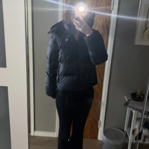 Svart dunjacka från Calvin Klein - Snygg Calvin Klein jacka i nyskick endast andvänd några få gånger! Köpt för 1200kr. Skriv för mer info pris kan diskuteras. Varm och jätteskön insida, även bra fickor! 
