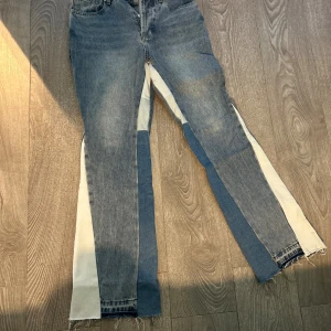 Gallery Dept. jeans med kontrastpaneler - Unika jeans från Gallery Dept. med blå denim och vita kontrastpaneler längs benen. Råa, fransiga benslut och klassisk femficksmodell. Snyggt statement-plagg med cool patchwork-känsla och tydlig logga i midjan.